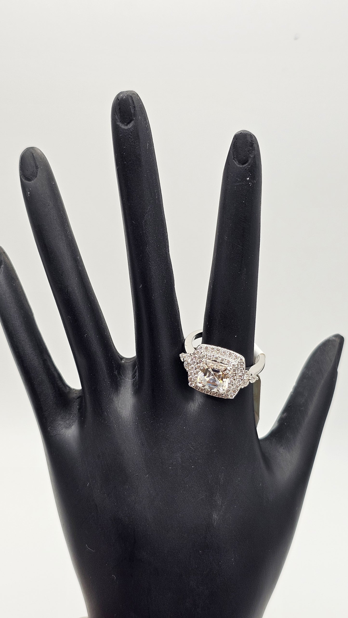 Diamond ring on a black mannequin hand against a white background